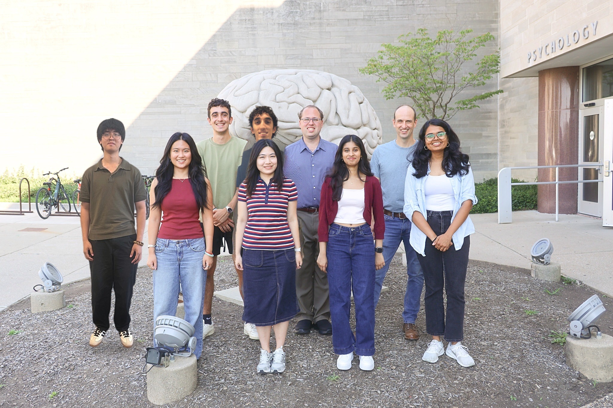 Lab group photo in front of the brain sculpture at the Psychology building